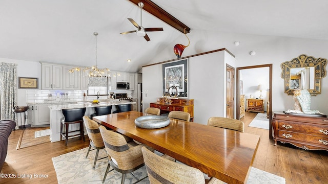 dining space with ceiling fan with notable chandelier, high vaulted ceiling, beam ceiling, and light wood-style flooring