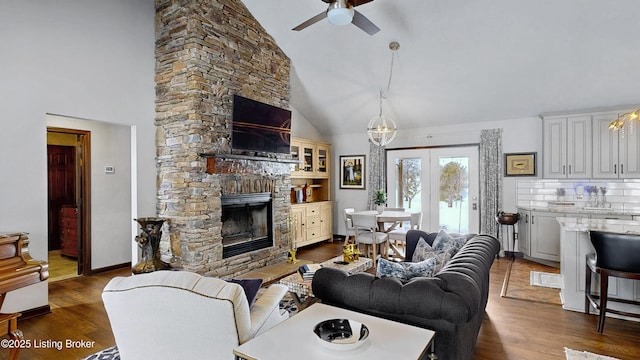 living area featuring baseboards, a ceiling fan, dark wood-style flooring, a fireplace, and high vaulted ceiling