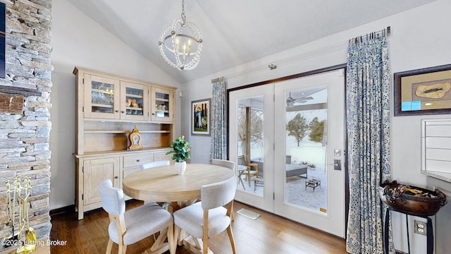 dining space with visible vents, a chandelier, vaulted ceiling, and dark wood finished floors