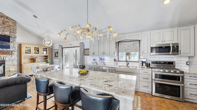 kitchen with a center island, decorative light fixtures, stainless steel appliances, glass insert cabinets, and a sink