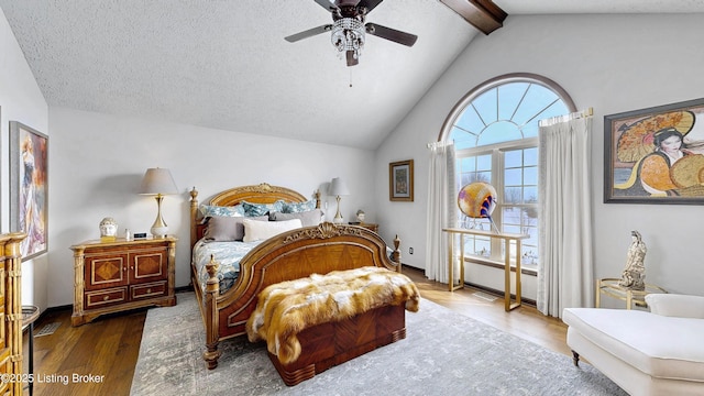 bedroom with dark wood-type flooring, lofted ceiling with beams, a textured ceiling, and a ceiling fan