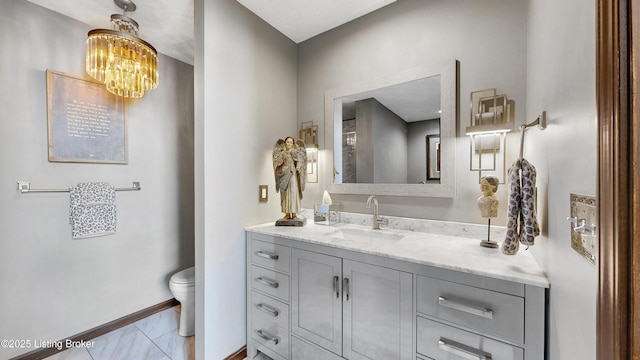 bathroom with toilet, an inviting chandelier, baseboards, and vanity