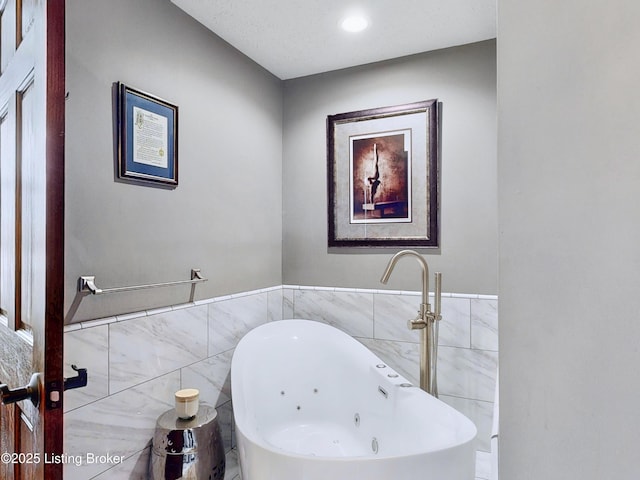 full bath with tile walls and a jetted tub