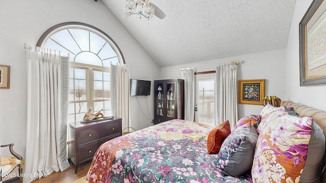 bedroom featuring lofted ceiling, a textured ceiling, and light wood finished floors