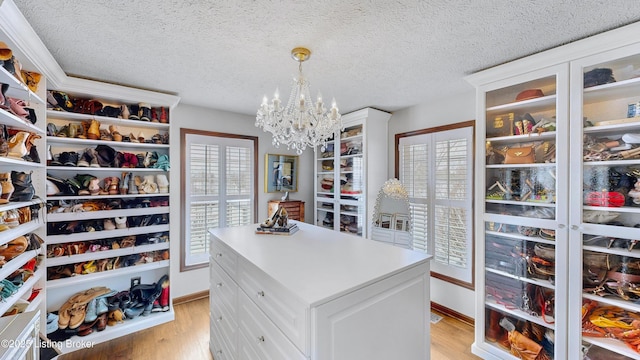 walk in closet with a notable chandelier and light wood finished floors