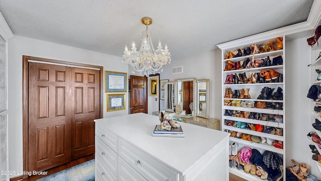 walk in closet with wood finished floors, visible vents, and an inviting chandelier