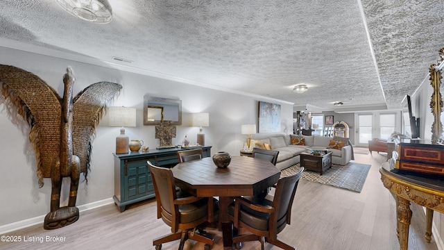 dining room with light wood finished floors, visible vents, ornamental molding, and baseboards