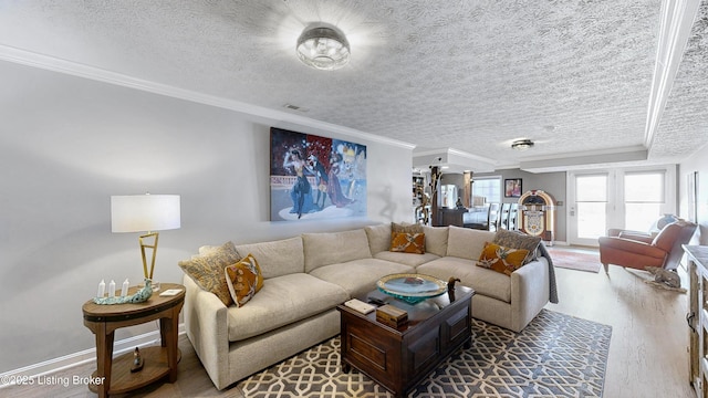 living area with baseboards, a textured ceiling, ornamental molding, and wood finished floors