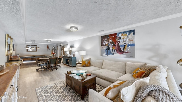 living area with a textured ceiling, wood finished floors, and crown molding