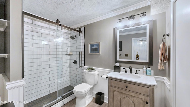 full bathroom with a textured ceiling, toilet, a wainscoted wall, ornamental molding, and a shower stall