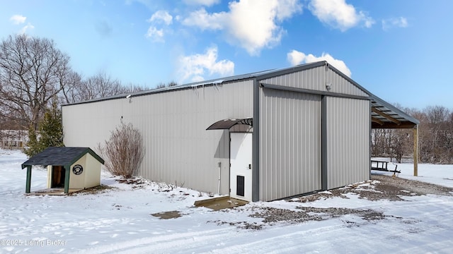 snow covered structure featuring a pole building and an outdoor structure