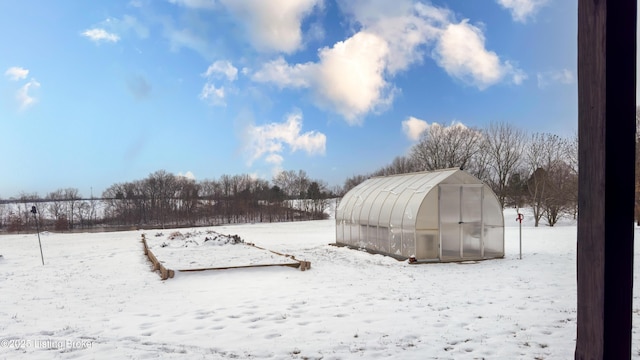 yard layered in snow with a greenhouse and an outbuilding