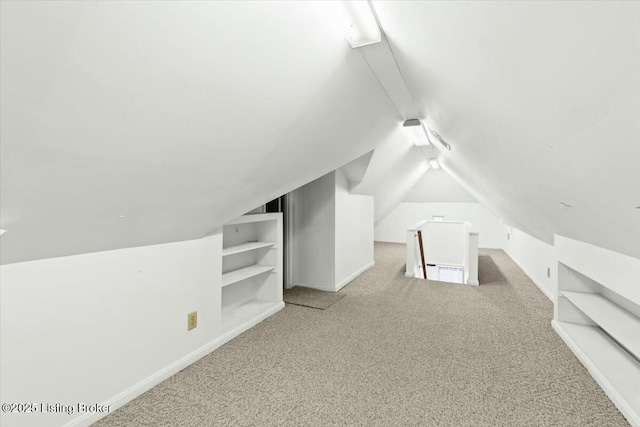 bonus room with vaulted ceiling and carpet floors