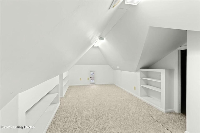 bonus room with light carpet, built in shelves, and lofted ceiling