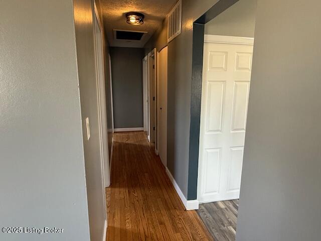 hall with dark wood-type flooring and a textured ceiling