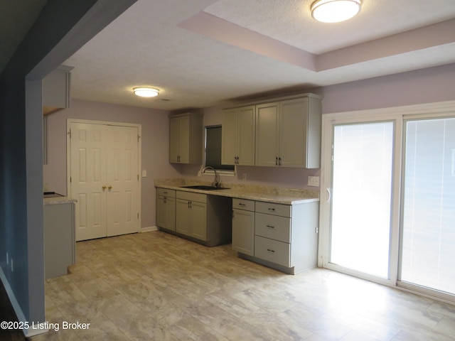 kitchen featuring sink, gray cabinetry, a textured ceiling, and a tray ceiling