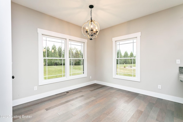 empty room featuring wood-type flooring and a chandelier