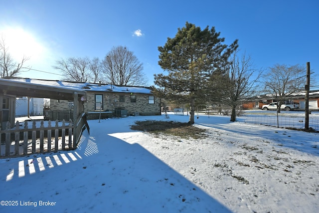 snowy yard featuring a carport and fence