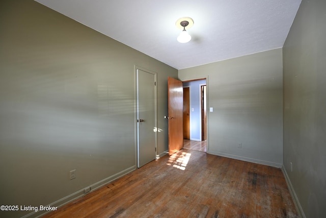 spare room featuring dark wood-style flooring and baseboards