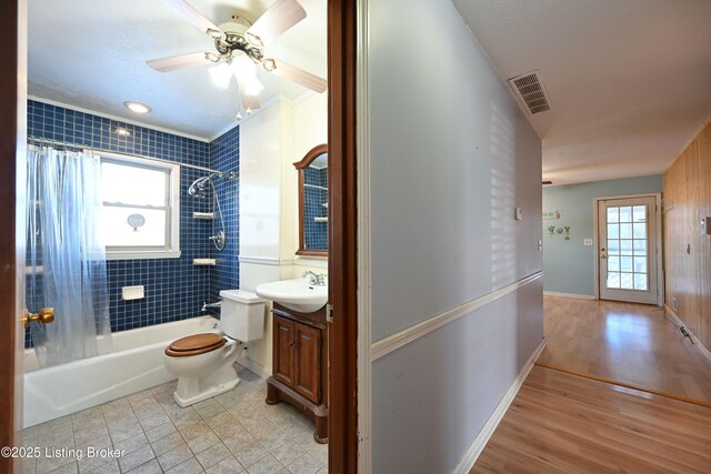 bathroom featuring visible vents, shower / bathtub combination with curtain, toilet, vanity, and wood finished floors