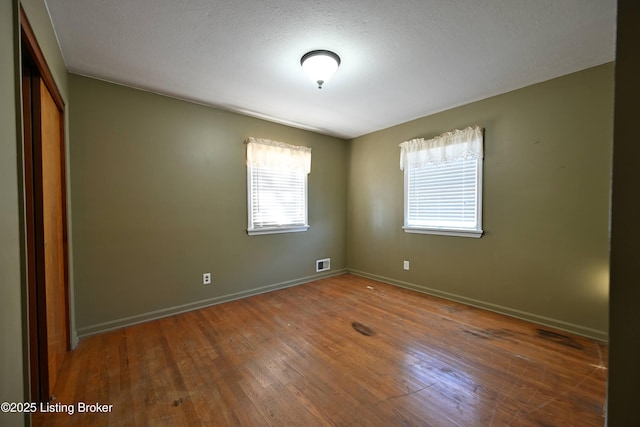 unfurnished room featuring visible vents, dark wood finished floors, and baseboards