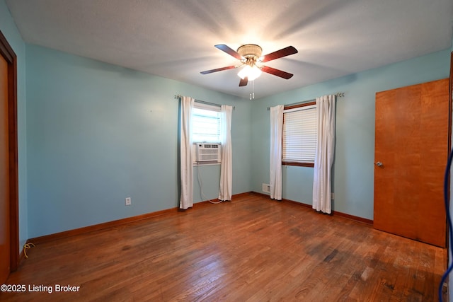 unfurnished bedroom with cooling unit, ceiling fan, baseboards, and wood finished floors