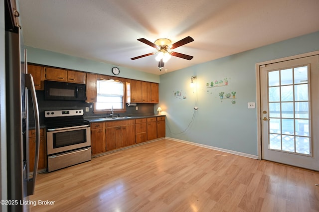 kitchen featuring stainless steel appliances, brown cabinetry, dark countertops, and a sink