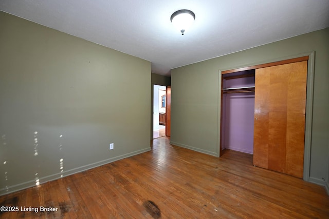 unfurnished bedroom with a closet, baseboards, and wood finished floors