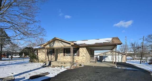 view of front facade with an outbuilding, brick siding, a porch, a carport, and driveway