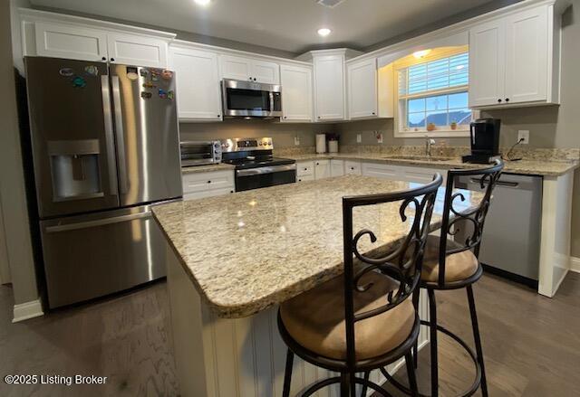 kitchen with white cabinetry, sink, stainless steel appliances, and a kitchen island