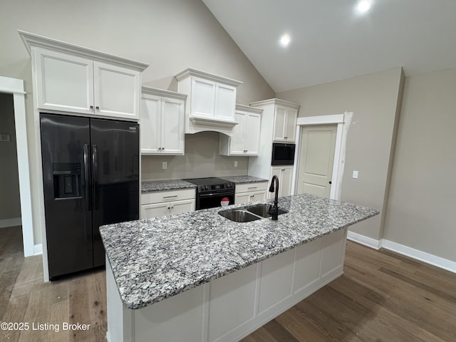 kitchen with dark wood-type flooring, sink, black appliances, a center island with sink, and white cabinets