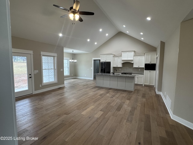 kitchen featuring hardwood / wood-style floors, sink, white cabinets, a kitchen island with sink, and black refrigerator with ice dispenser