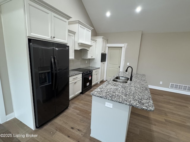 kitchen with sink, light stone counters, black appliances, a kitchen island with sink, and white cabinets