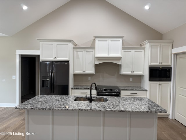 kitchen featuring black fridge, white cabinets, sink, and built in microwave