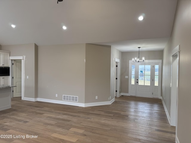 entrance foyer featuring an inviting chandelier and wood-type flooring