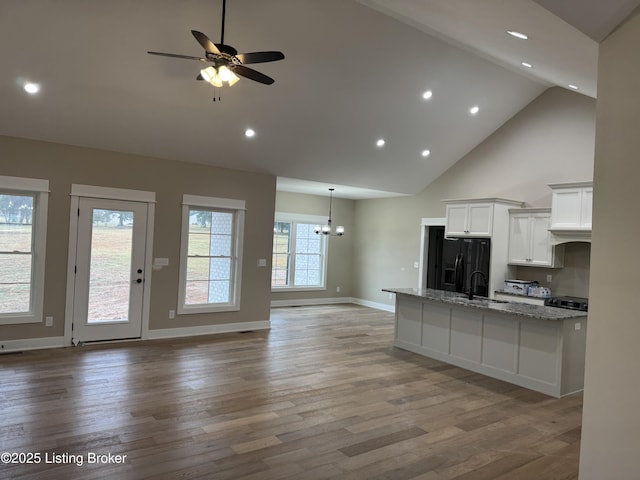 kitchen featuring sink, white cabinets, light stone counters, black fridge with ice dispenser, and light wood-type flooring