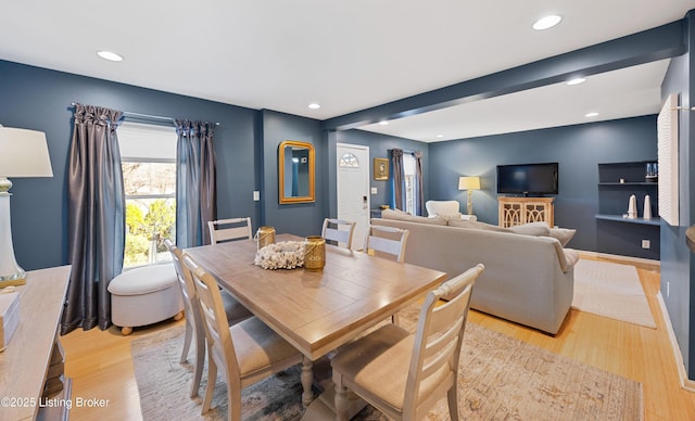 dining room with beamed ceiling and light wood-type flooring