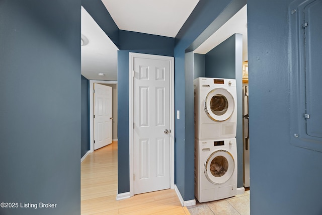 laundry room featuring stacked washer / drying machine and light hardwood / wood-style floors