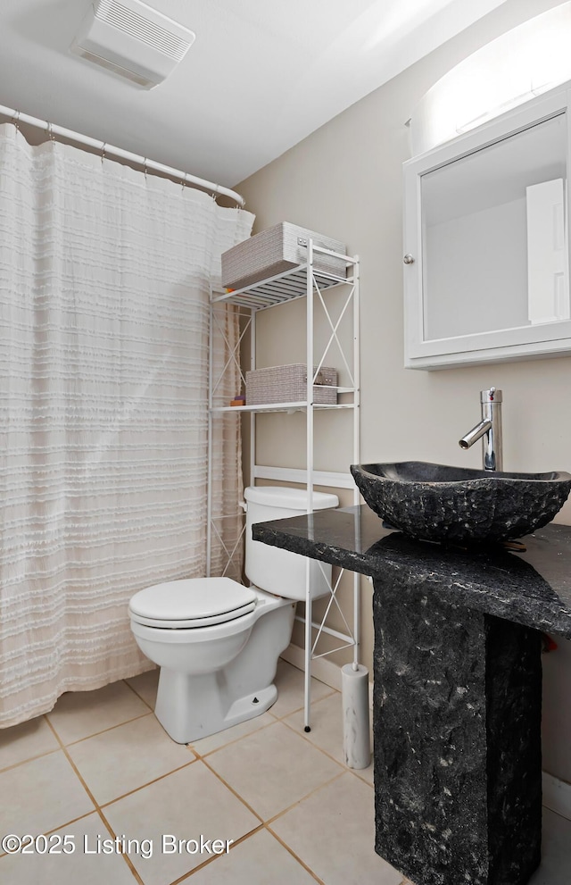 bathroom with toilet, sink, and tile patterned flooring