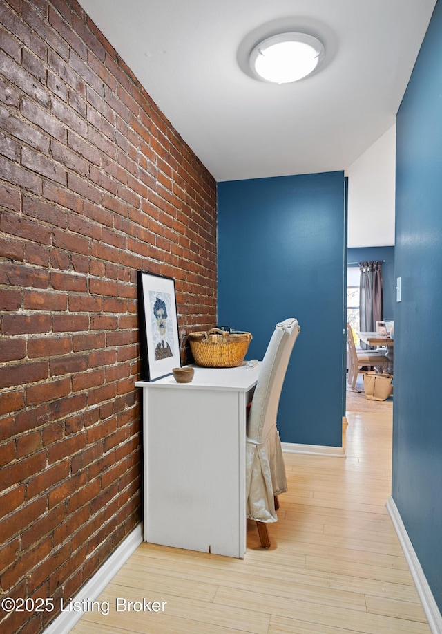 interior space with light hardwood / wood-style flooring and brick wall