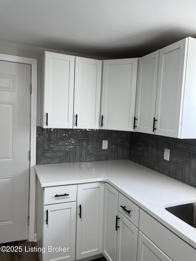 kitchen with white cabinets, light countertops, and backsplash