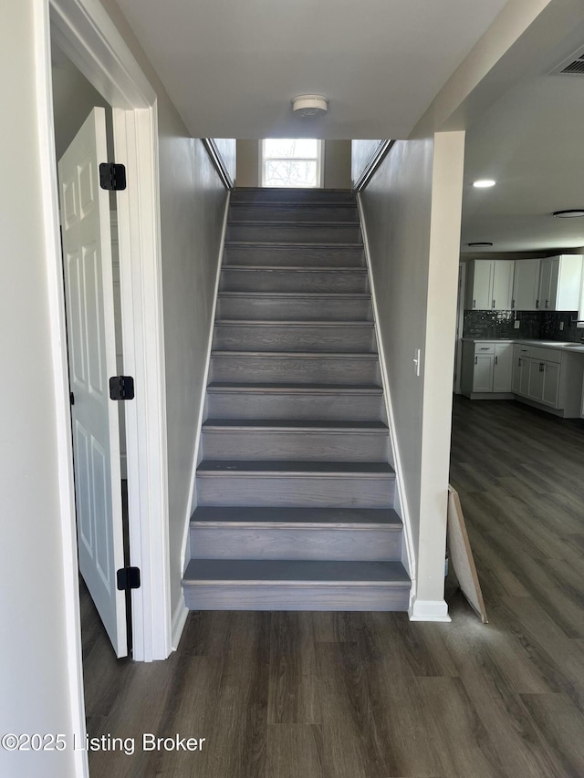 stairway with wood finished floors, visible vents, and baseboards