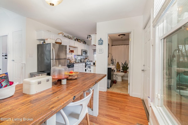 kitchen with light wood-style floors, white cabinetry, and appliances with stainless steel finishes