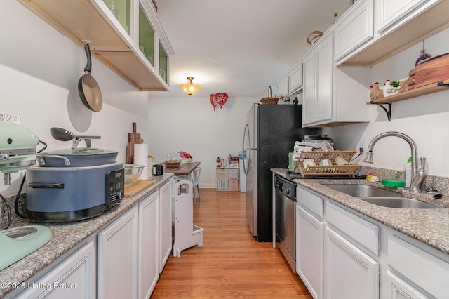 kitchen with light wood finished floors, open shelves, white cabinets, a sink, and dishwasher