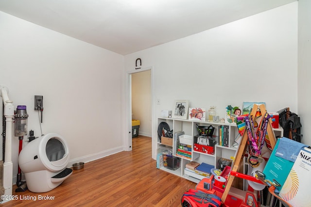 recreation room featuring baseboards and wood finished floors