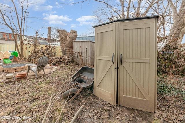 view of shed with a fire pit and fence