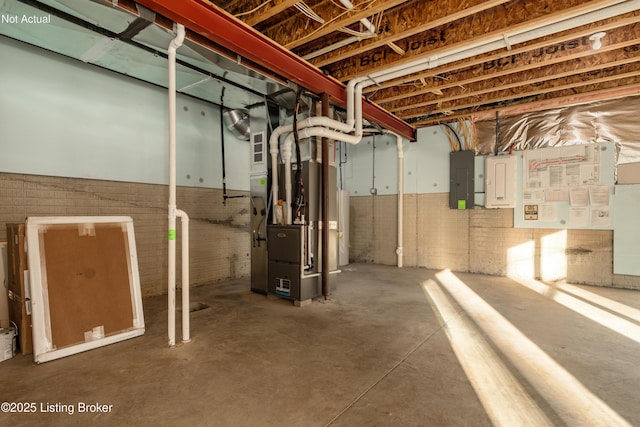 basement featuring brick wall, electric panel, and heating unit