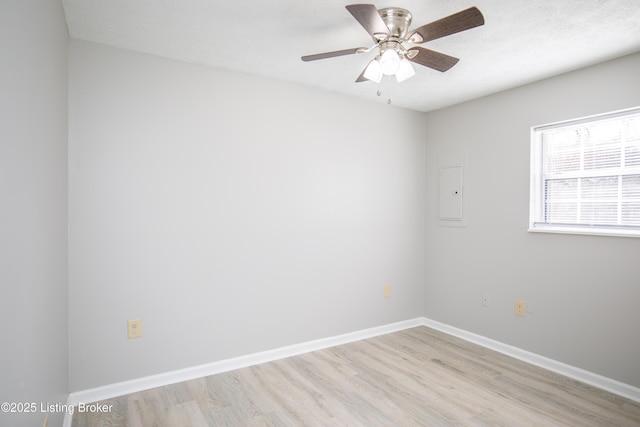 spare room with light wood finished floors, a ceiling fan, a textured ceiling, electric panel, and baseboards