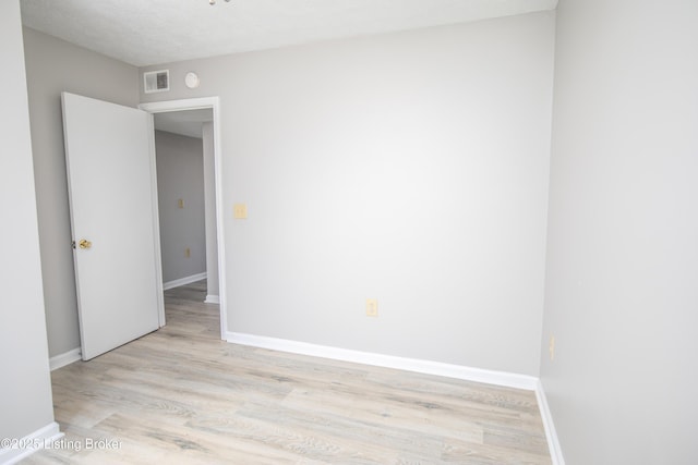 empty room featuring light wood-type flooring, baseboards, and visible vents