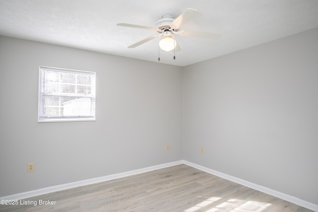 empty room with a ceiling fan, light wood-style flooring, baseboards, and a textured ceiling